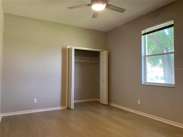 an empty room with a chandelier fan and closet area
