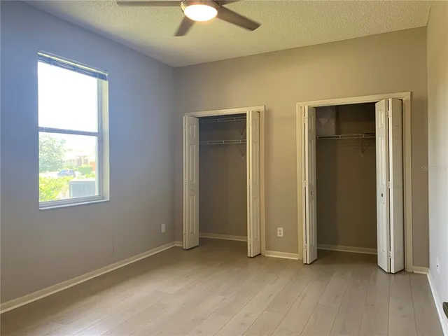 an empty room with windows closet and chandelier fan