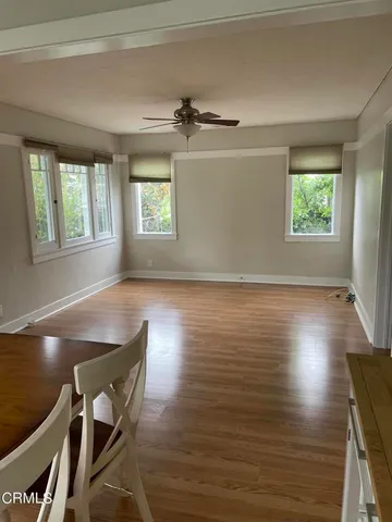 a view of a room with wooden floor a ceiling fan and windows