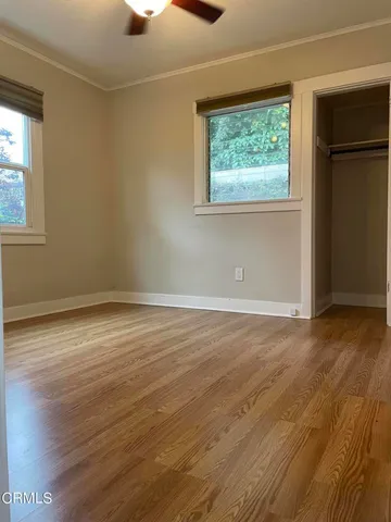an empty room with wooden floor cabinet and windows
