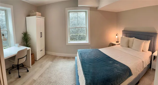 a bedroom with a bed windows and a chair