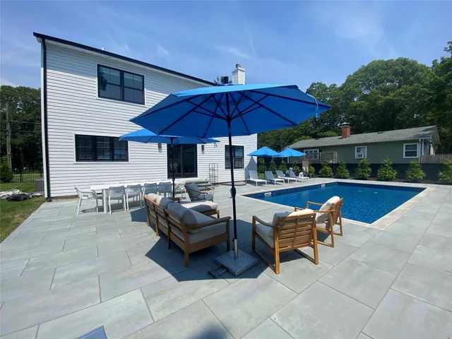 a view of a patio with dining table and chairs under an umbrella