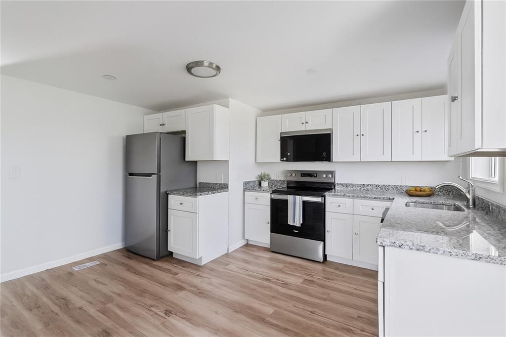 1460 Guffey Road Irwin, PA 15642 - Photo 10 of 33 a kitchen with a refrigerator stove and white cabinets