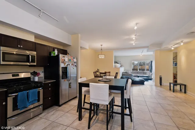 a kitchen with a dining table chairs and refrigerator