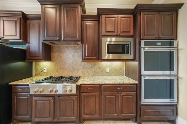 a kitchen with granite countertop a refrigerator a stove a kitchen island a dining table and chairs