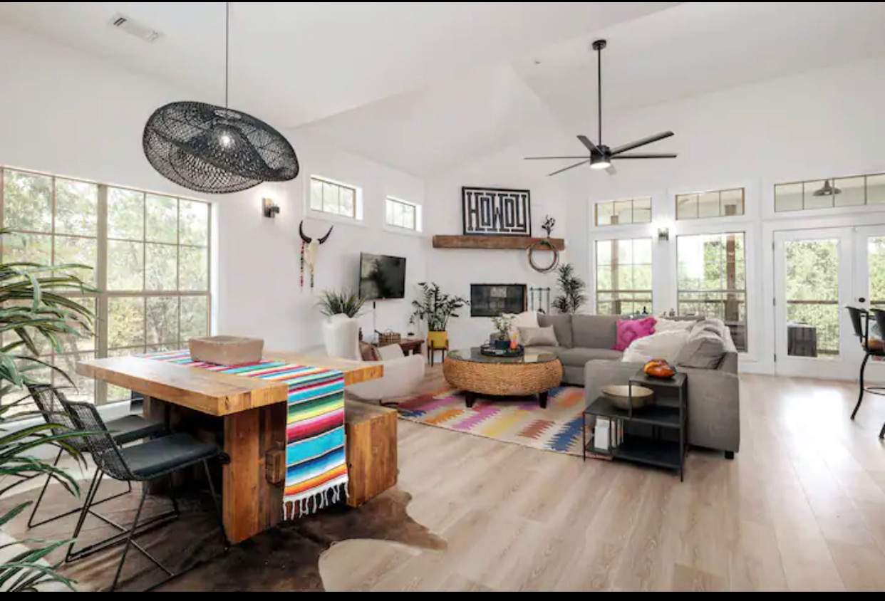 Living area featuring high vaulted ceiling, plenty of natural light, wood finished floors, ceiling fan, and french doors