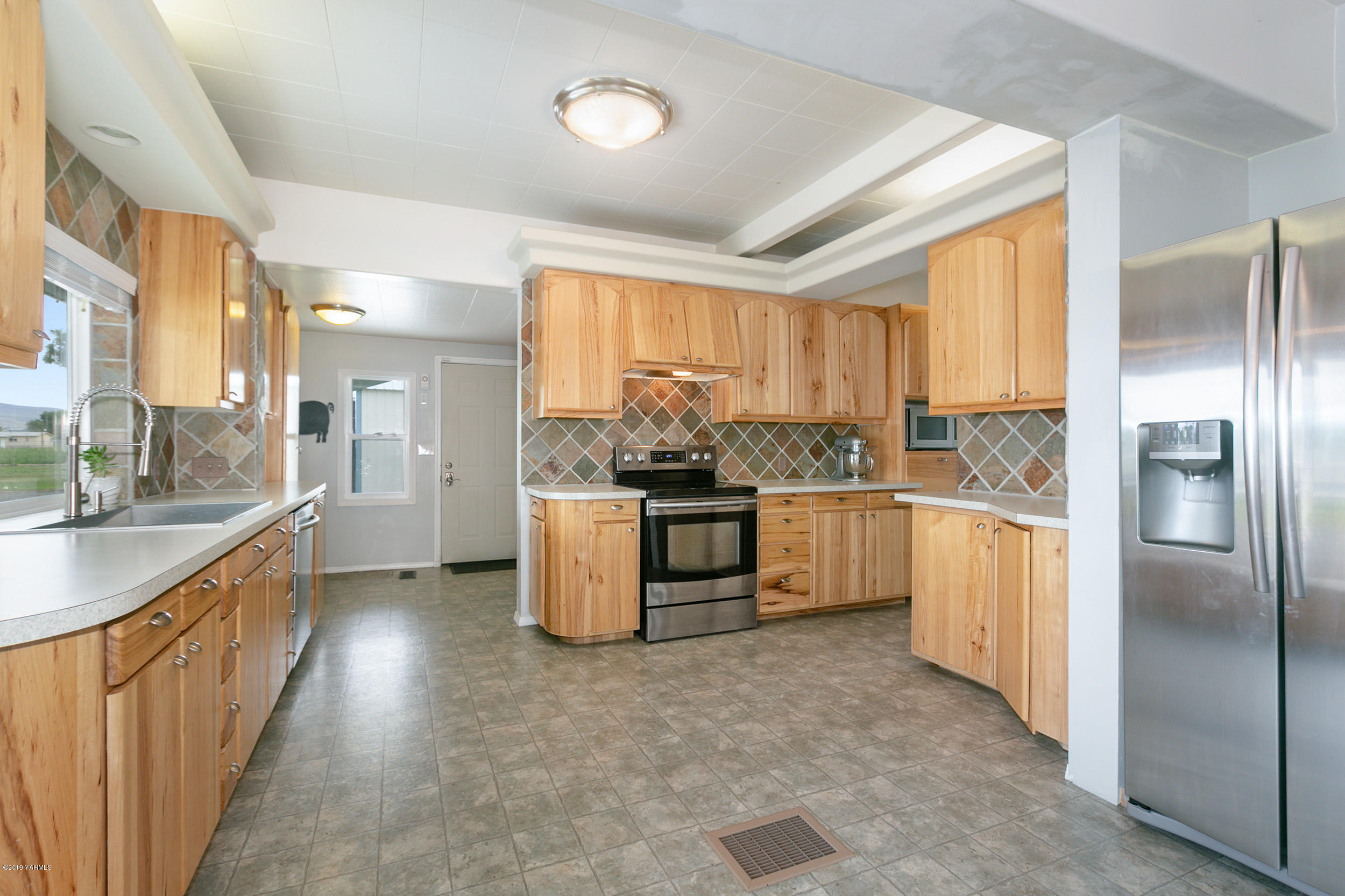 3551 Birchfield Road Moxee, WA 98936 - Photo 14 of 24 a kitchen with granite countertop a refrigerator a sink a counter top space and cabinets