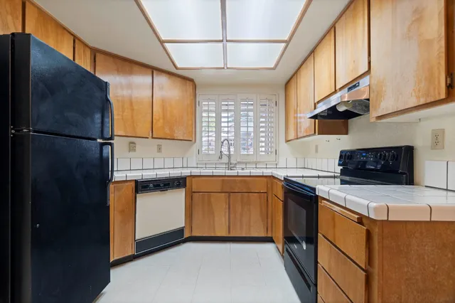 a kitchen with stainless steel appliances granite countertop a sink a stove a refrigerator a washer dryer and white cabinets