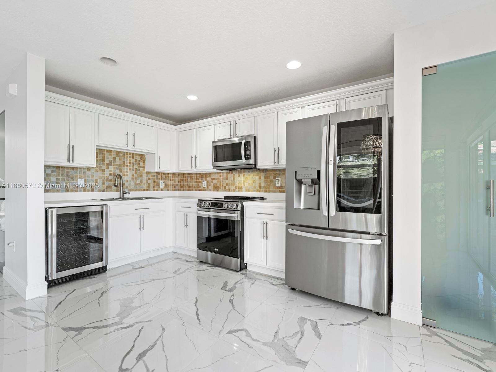 16544 Southwest 68th Terrace Miami, FL 33193 - Photo 13 of 32 a kitchen with white cabinets and stainless steel appliances