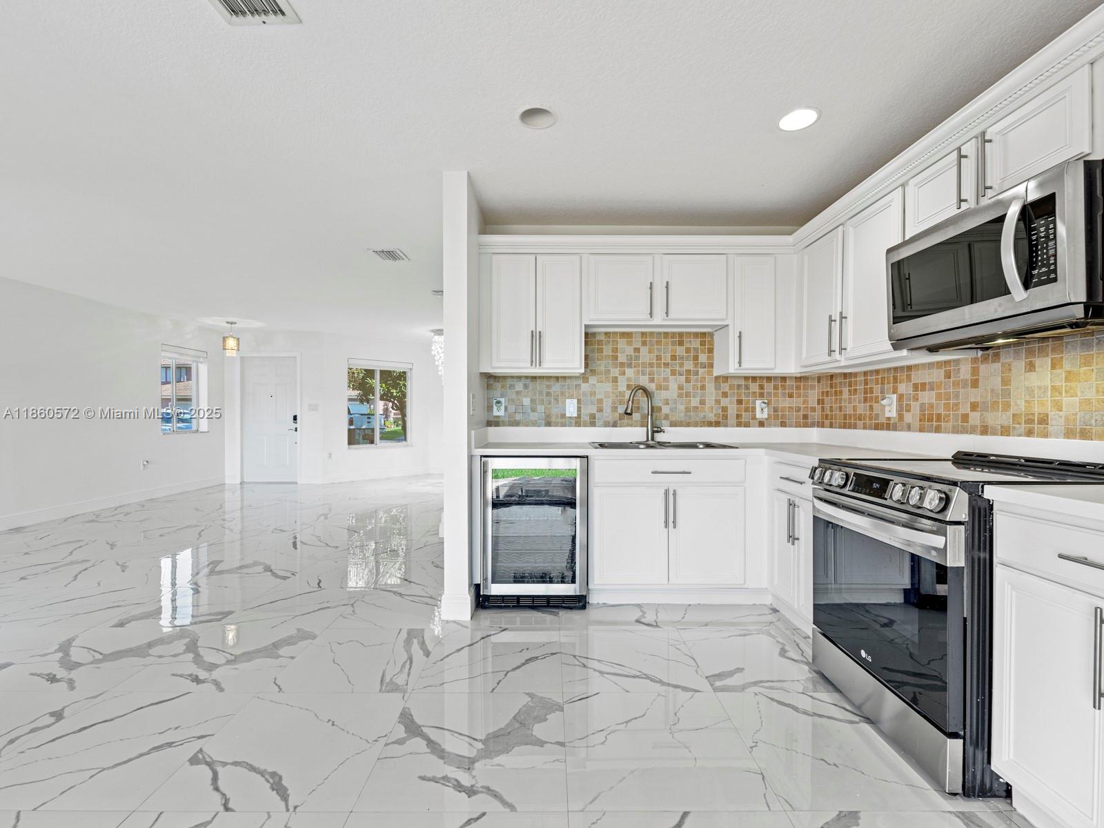 16544 Southwest 68th Terrace Miami, FL 33193 - Photo 14 of 32 a kitchen with granite countertop a stove a sink and a microwave