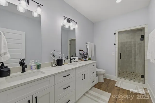 a bathroom with double vanity sinks a shower and a mirror