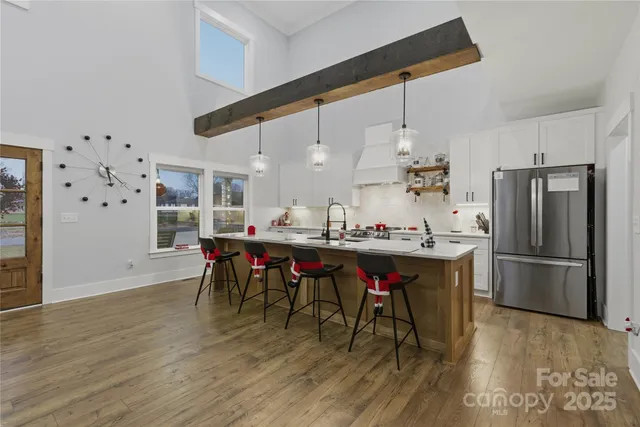a kitchen with stainless steel appliances kitchen island a table chairs and a refrigerator