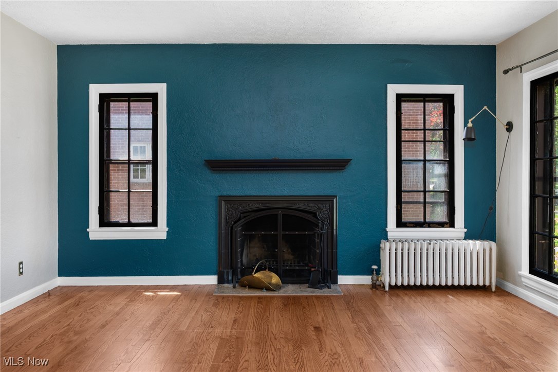 3677 Traver Road Shaker Heights, OH 44122 - Photo 5 of 35 Unfurnished living room with radiator heating unit, an accent wall, wood finished floors, and healthy amount of natural light