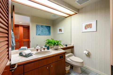 a bathroom with a granite countertop sink mirror and toilet