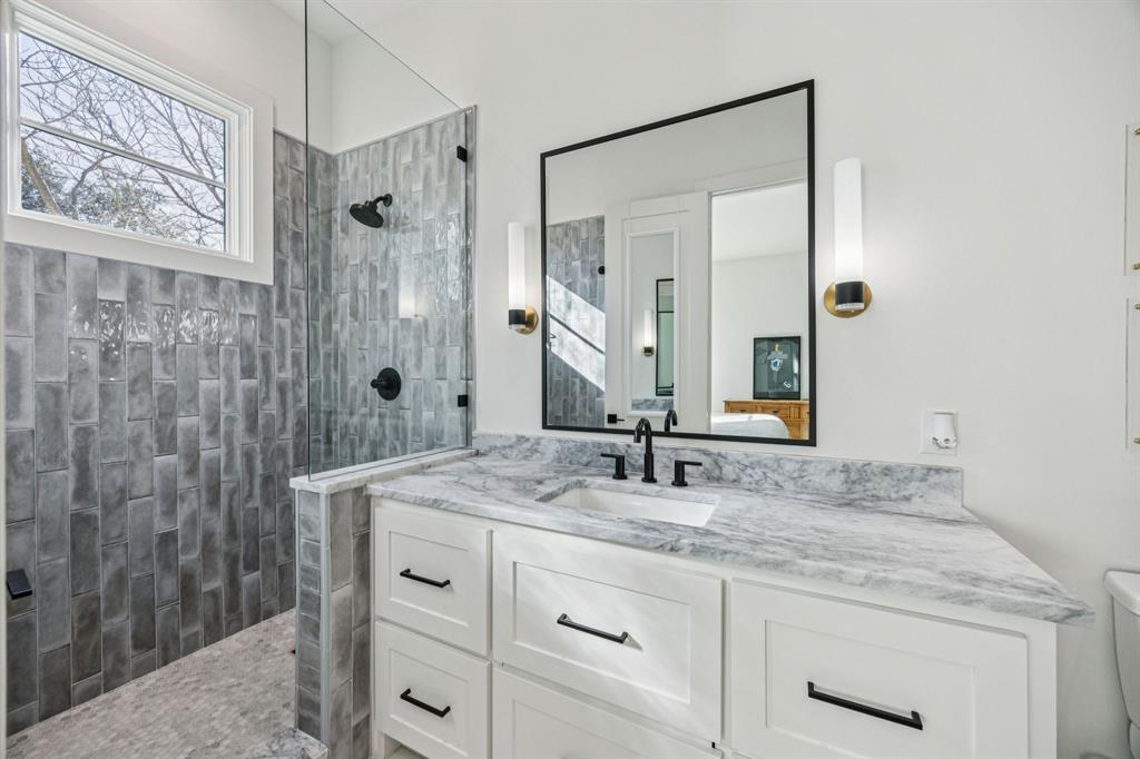 8427 Midway Road Dallas, TX 75209 - Photo 26 of 37 a bathroom with a granite countertop sink a mirror a vanity and a shower