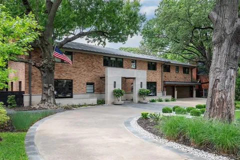 a front view of a house with garden and trees