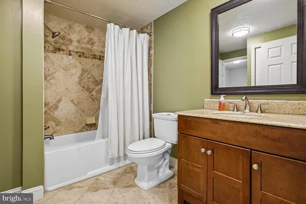 a bathroom with a granite countertop toilet sink and mirror