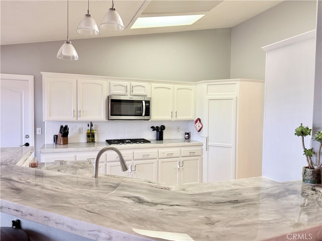 7915 Outpost Road Oak Hills, CA 92344 - Photo 12 of 54 a kitchen with granite countertop a sink stainless steel appliances and white cabinets