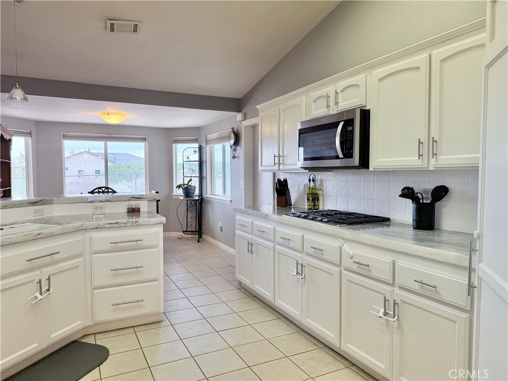 7915 Outpost Road Oak Hills, CA 92344 - Photo 13 of 54 a kitchen with stainless steel appliances granite countertop white cabinets a sink and dishwasher