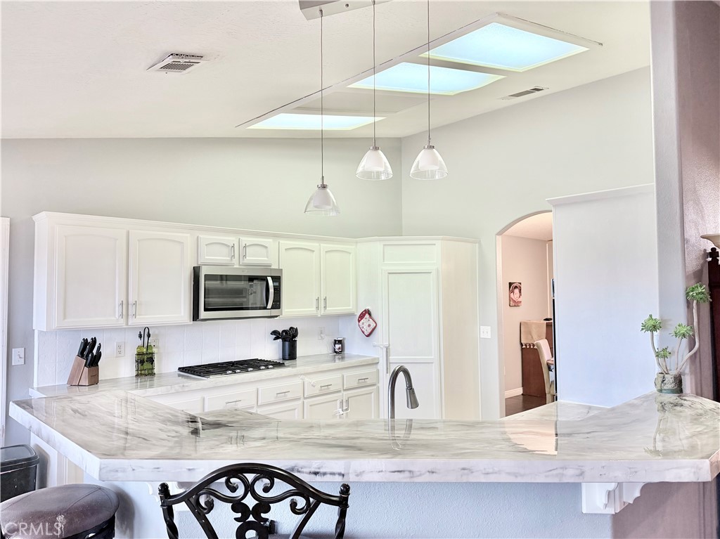 7915 Outpost Road Oak Hills, CA 92344 - Photo 3 of 54 a kitchen with stainless steel appliances granite countertop a sink a stove a microwave oven with white cabinets and granite countertops