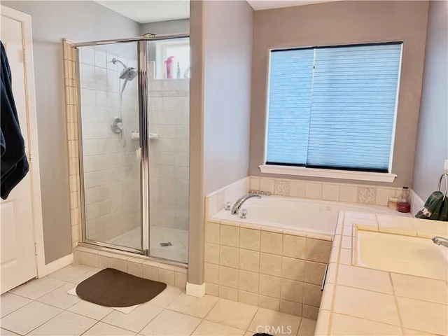 a bedroom with a large bed a flat tv screen and a chandelier