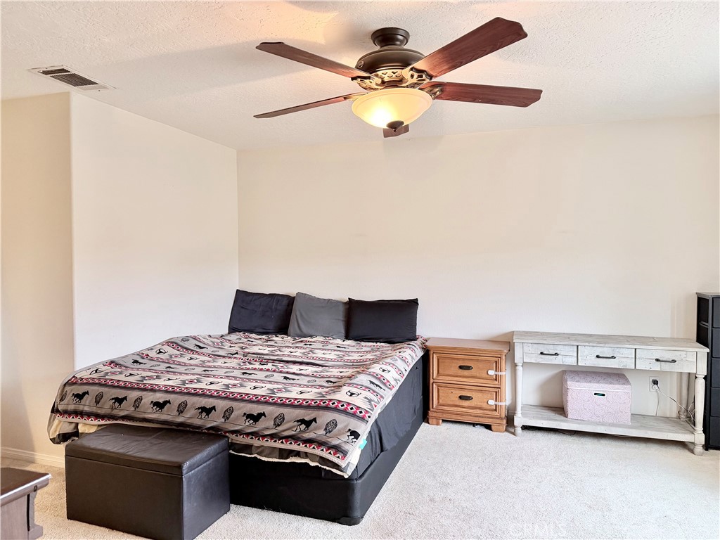 7915 Outpost Road Oak Hills, CA 92344 - Photo 38 of 54 a bedroom with a bed and a chandelier