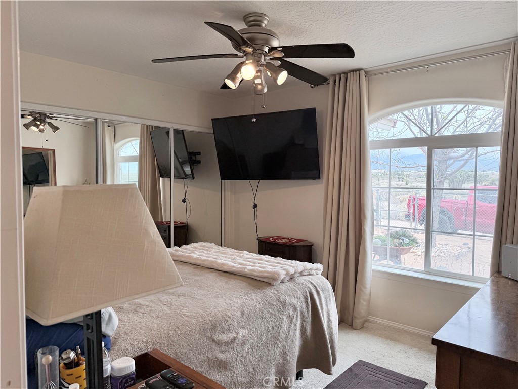 7915 Outpost Road Oak Hills, CA 92344 - Photo 39 of 54 a bedroom with a large bed a flat tv screen and a chandelier