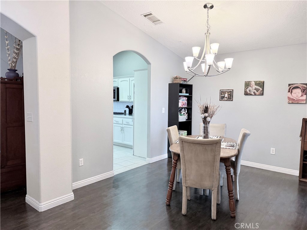 7915 Outpost Road Oak Hills, CA 92344 - Photo 8 of 54 a view of a dining room with furniture a chandelier and wooden floor