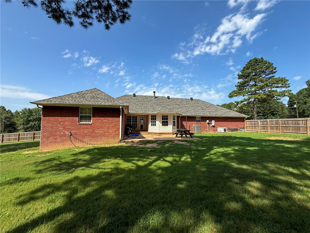 70 Walthall Road Russellville, AR 72802 - Photo 48 of 51 Expansive backyard featuring a red brick exterior, a wood privacy fence, a multi-pane glass door, and a shingled roof