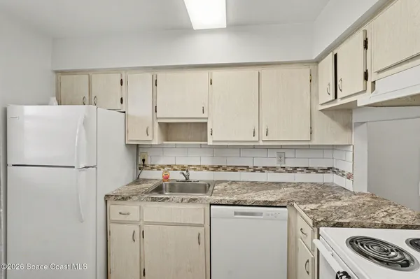 a white kitchen with granite countertop white cabinets and white appliances