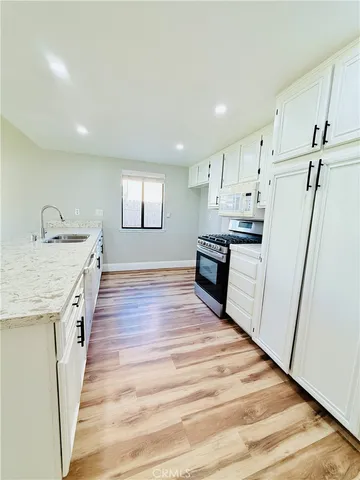 a kitchen with granite countertop kitchen island wooden floors appliances and cabinets