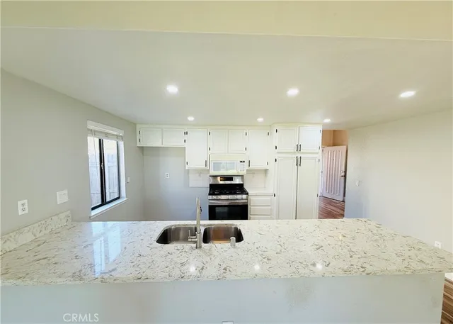 a large white kitchen with kitchen island a sink stainless steel appliances and cabinets