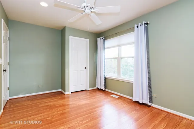 an empty room with wooden floor fan and windows