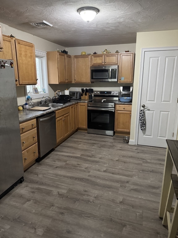 89 Main Street Rowley, MA 01969 - Photo 11 of 39 a kitchen with stainless steel appliances kitchen island granite countertop a stove a sink and a microwave