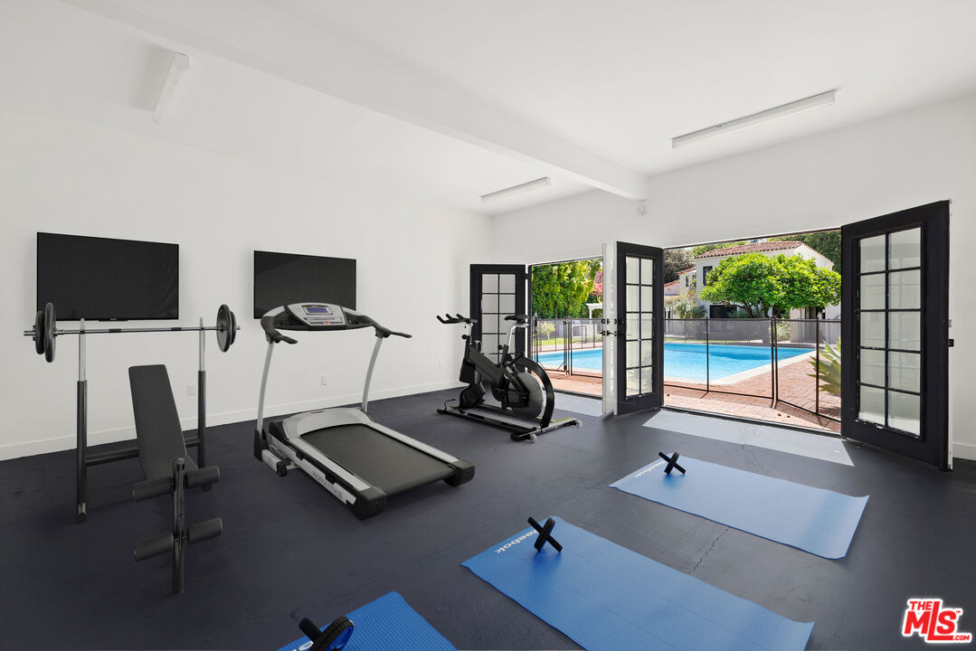 712 North Rodeo Drive Beverly Hills, CA 90210 - Photo 34 of 36 a room with gym equipment and a flat screen tv