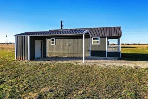 323 Blue Cat Boulevard Haskell, TX 79521 - Photo 15 of 18 Property exterior featuring a dark gray corrugated metal roof, gray vertical siding, and a covered porch with white railings