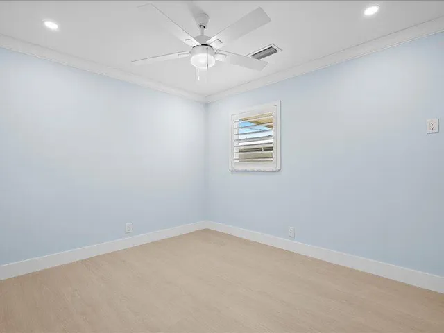 an empty room with a window and a fan