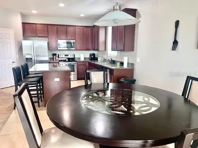 a kitchen with stainless steel appliances granite countertop a table chairs microwave and refrigerator