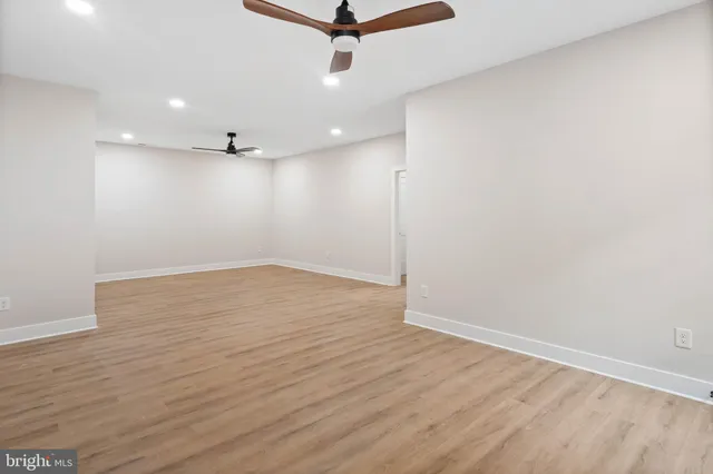 an empty room with wooden floor and a ceiling fan