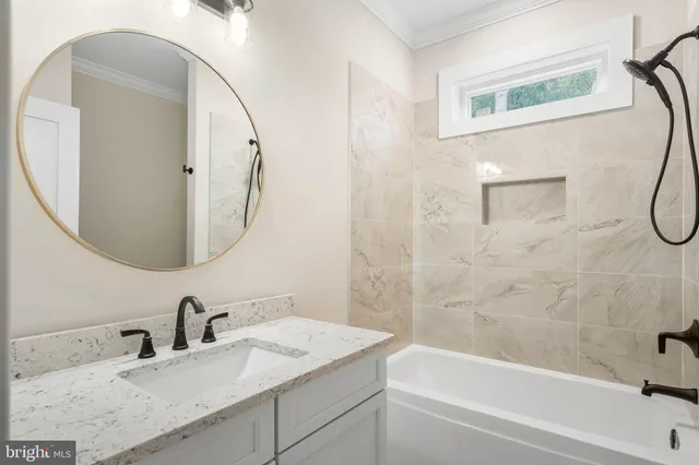 a bathroom with a granite countertop sink a mirror and a bathtub