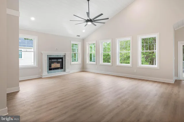 an empty room with windows a fireplace and a ceiling fan