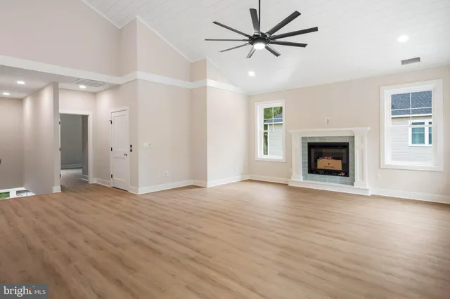 a view of an empty room with wooden floor fireplace and a window