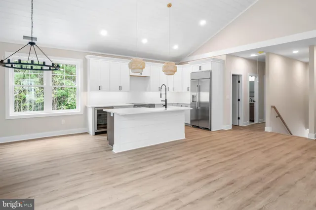 a large kitchen with stainless steel appliances granite countertop a stove a refrigerator a sink dishwasher and a fireplace with wooden floor