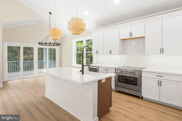 a large kitchen with stainless steel appliances granite countertop a sink a stove and a wooden floors