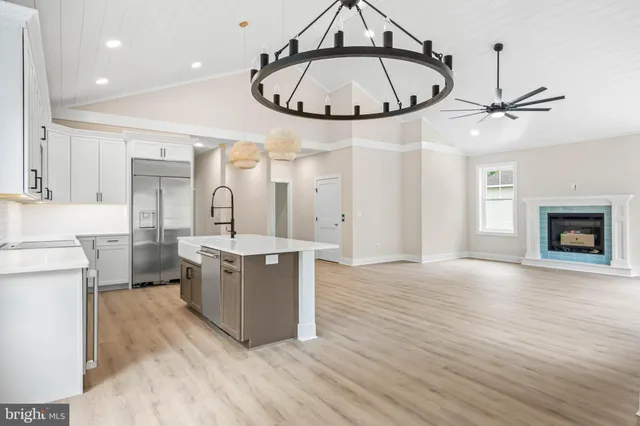 an empty room with wooden floor chandelier fan and windows