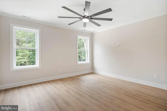 an empty room with wooden floor and fan