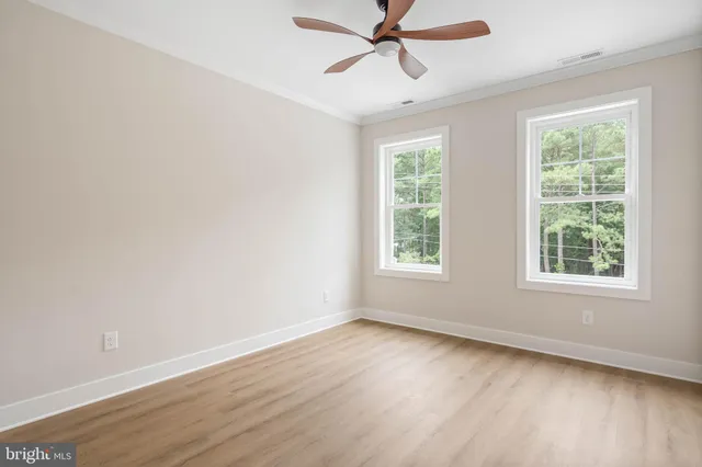 an empty room with wooden floor cabinet and a ceiling fan