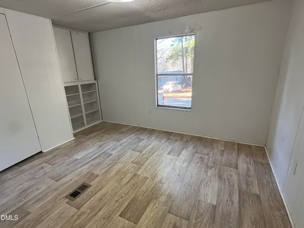 an empty room with wooden floor and window