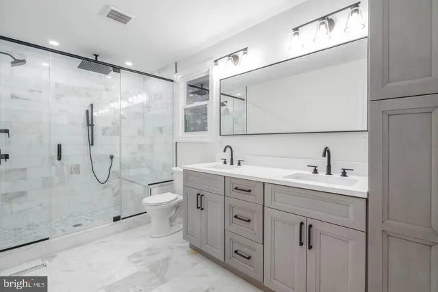 a bathroom with a double vanity sink toilet mirror and shower