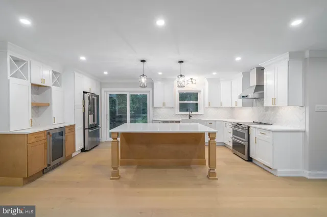 a large kitchen with kitchen island a sink white cabinets and stainless steel appliances
